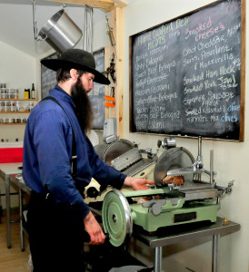 Matt Secich uses a hand-powered slicer to cut bacon at his Charcuterie shop. David Leaming/Staff Photographer