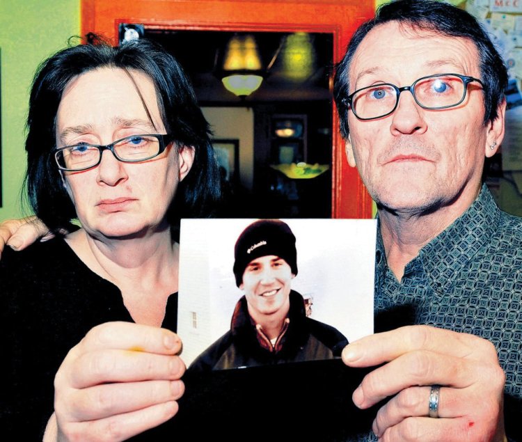 Lorna and Michael Smilek hold a 2006 photograph of Michael’s son Justin Crowley-Smilek, who was shot and killed after he confronted Farmington police. Staff photo by David Leaming