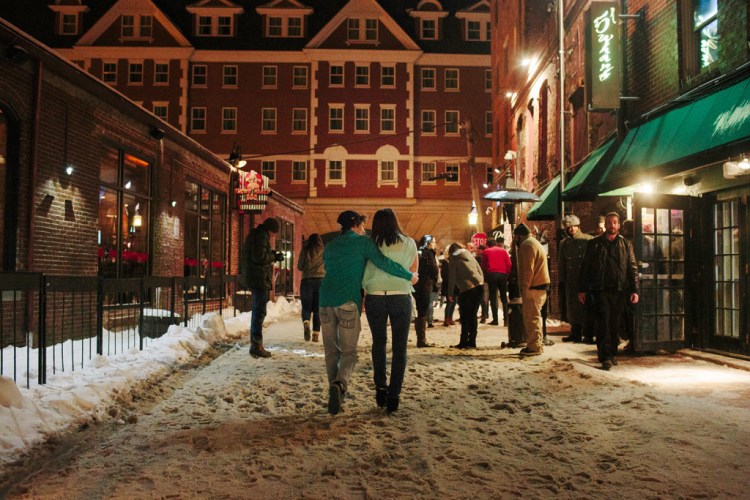 Patrons of bars and nightclubs along Wharf Street in Portland walk outside after bars close at 1 a.m., with the Portland Harbor Hotel in the background. A group is trying to find a compromise between the popular nightclubs and nearby hotels, whose patrons often complain about noise.