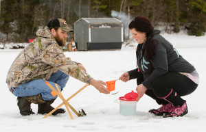 A shiner escapes in the exchange from Lacey Lang to her boyfriend, Tim Hansen, while they ice fish Tuesday on Pequawket Pond in Limington. Lang said she won't fish on ice that's less than 6 to 8 inches thick. Carl D. Walsh/Staff Photographer