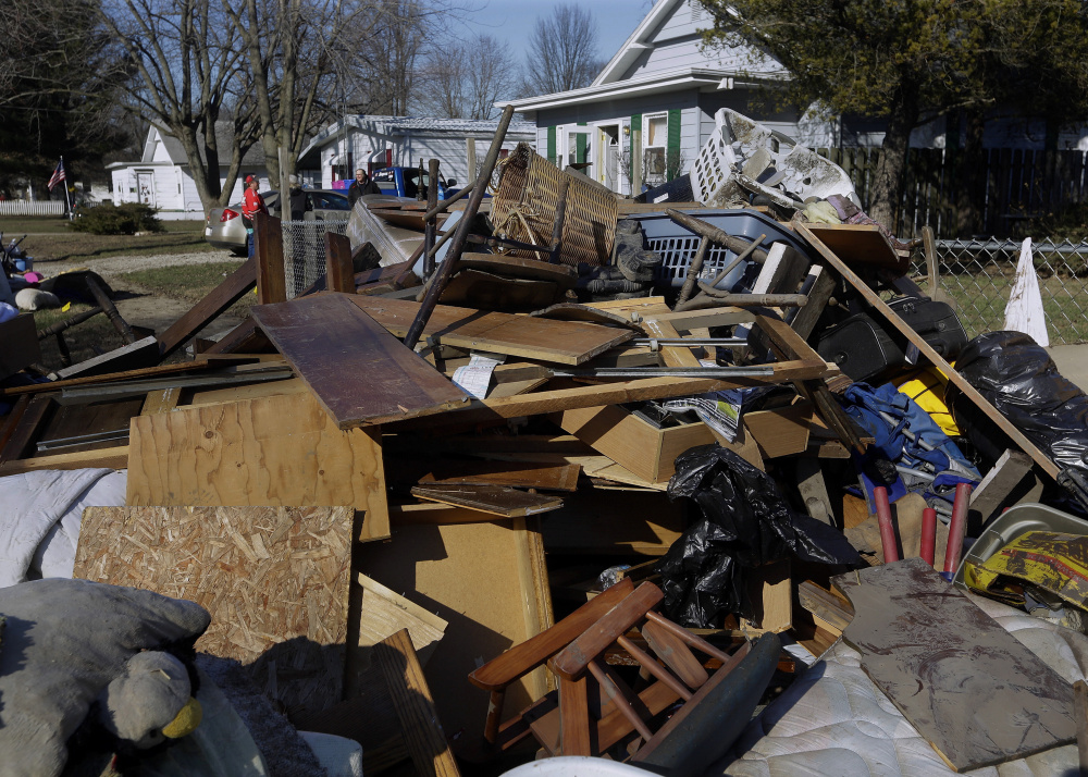 Central Illinois residents pile ruined furniture, appliances and clothes along the street for disposal crews to pick up Sunday after last week’s flooding from the south fork of the Sangamon River in Kincaid, Ill.
