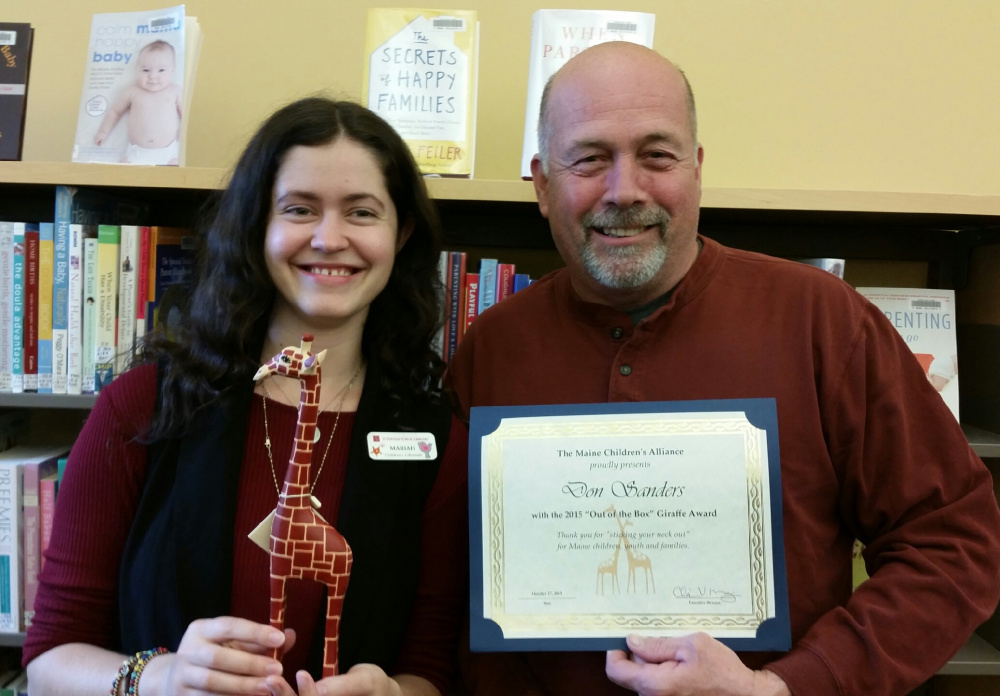 Topsham Public Library children’s librarian Mariah Sewall presents longtime Topsham school bus driver Don Sanders with a Maine Children’s Alliance Giraffe Award, recognizing his efforts to promote literacy among young students through a  book bags program he created in conjunction with the library. Student commuters are invited to grab a book to read to themselves or to younger students when they board the bus.
