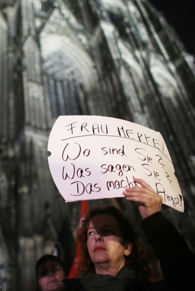 A woman protests  against sexism outside the cathedral in Cologne, Germany,  Tuesday.  The poster reads: "Mrs. Merkel. Where are you? What do you say? It's scary."  German Chancellor Angela Merkel voiced outrage Tuesday at a series of sexual assaults in the western city of Cologne on New Year's Eve.  (Oliver Berg/dpa via AP)