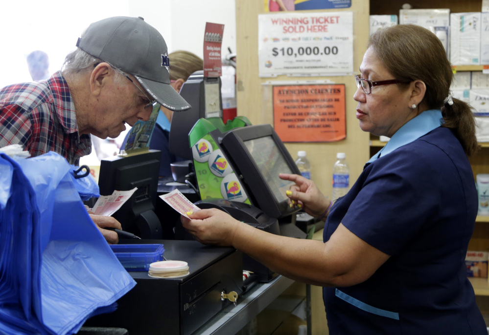 Pastora Garcia, right, sells Powerball tickets to a customer Saturday in Miami. Officials say it’s increasingly likely that someone will win the $900 million Powerball jackpot.