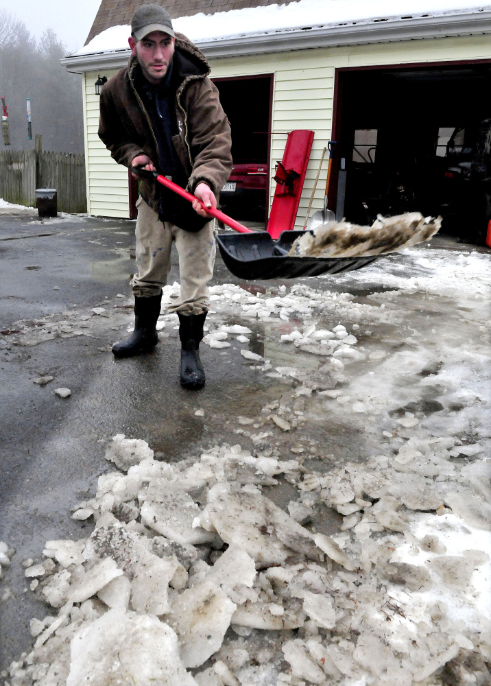 James Gray throws slush and chunks of ice that melted on the driveway at his home in Oakland on a warm and rainy Sunday. Monday should be much colder, with temperatures in the 30s in southern Maine. David Leaming/Morning Sentinel