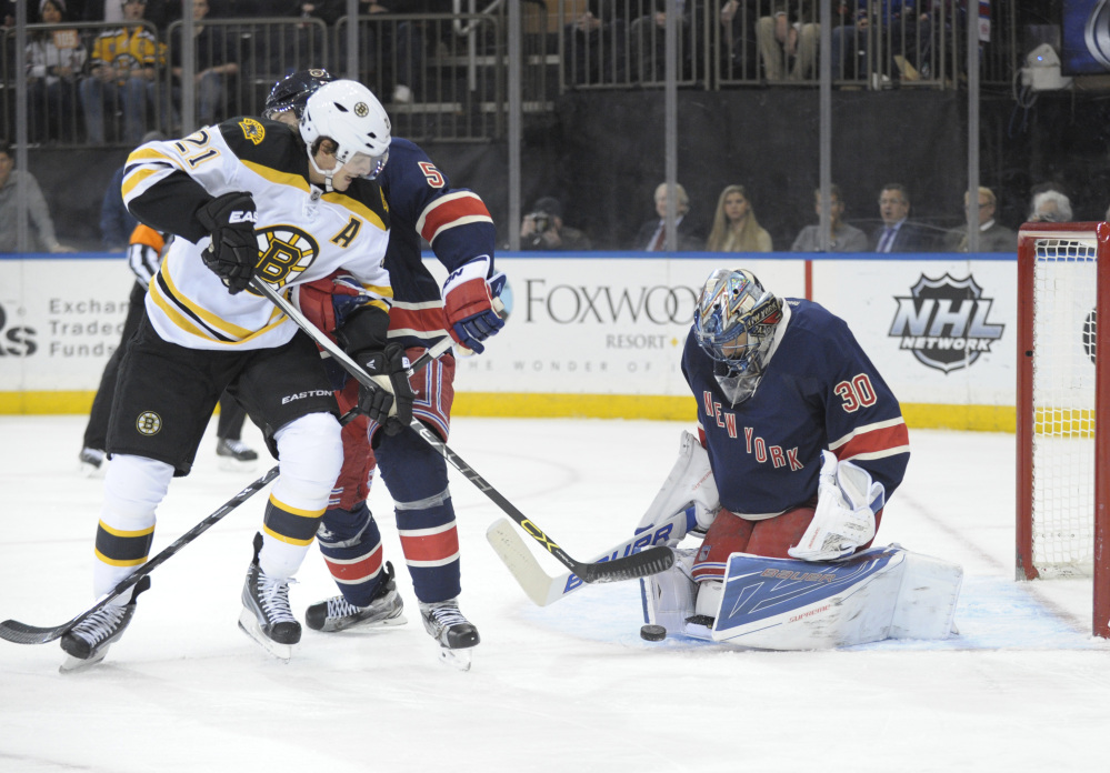Rangers’ goaltender Henrik Lundqvist makes a save on a shot by the Bruins’ Loui Eriksson, who is checked by the Rangers’ Dan Girardi in the first period of Monday night’s game in New York.