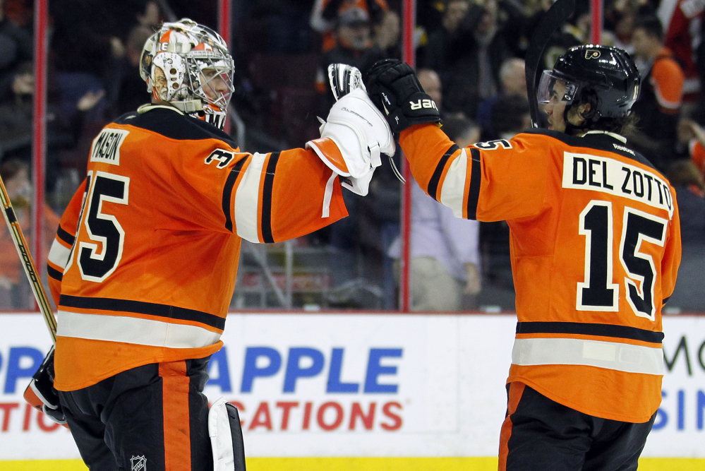 The Flyers’ Steve Mason, left, and Michael Del Zotto high-five at the end of their win over the Bruins. It was the Flyers’ fourth straight win.