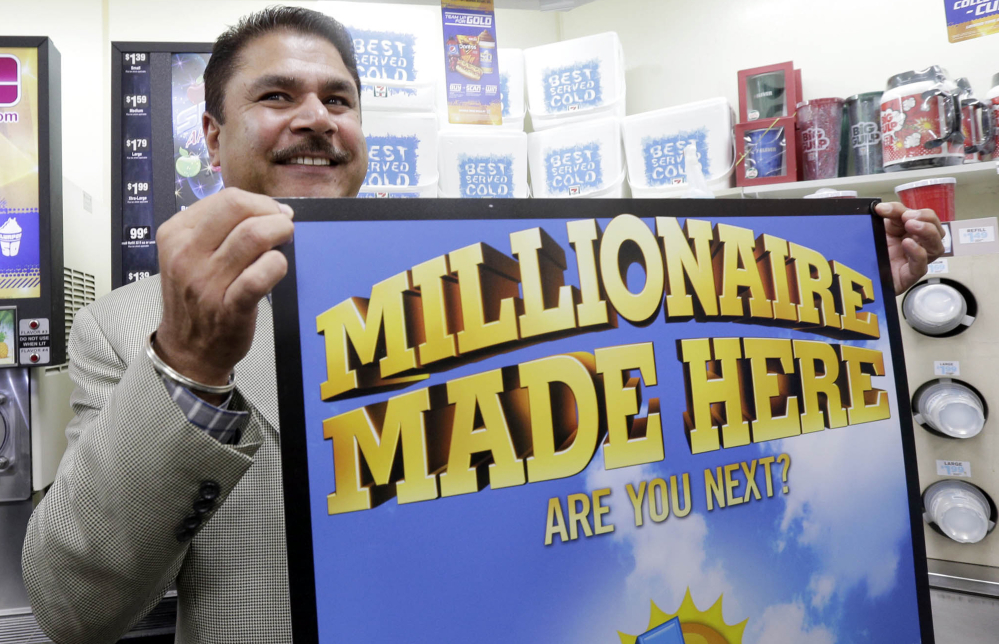 Balbir Atwal, the owner of a 7-Eleven store that sold a winning Powerball lottery ticket, holds up a Millionaire Made Here sign at his store in Chino Hills, Calif., Thursday.