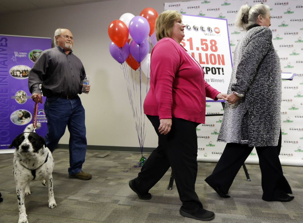 John Robinson brings in the family dog, Abby, as Robinson’s wife, Lisa, center, arrives for a news conference with Rebecca Hargrove, president and CEO of the Tennessee Lottery, on Friday in Nashville, Tenn.
