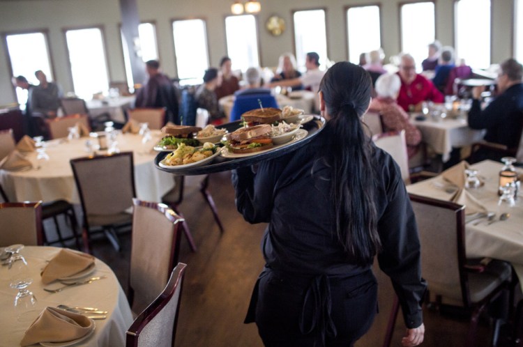 Dawn Murray, a server at DiMillo’s On the Water, carries food to waiting customers during the lunch rush Friday at the Portland restaurant. Her employer, Steve DiMillo, says, “It’s time for someone to make a call (about the legality of Portland’s wage ordinance), so they don’t leave operators or the wait staff not knowing what their pay should be.”