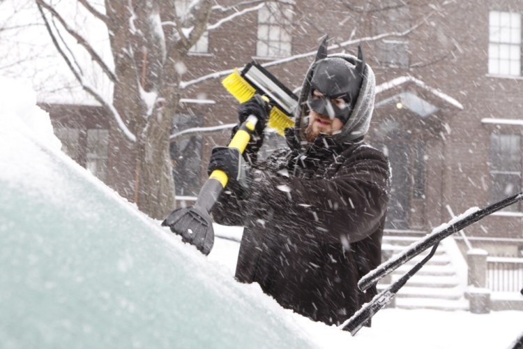 Spencer Holmes wears a Batman mask as he scrapes his windshield on Saturday in Portland.
