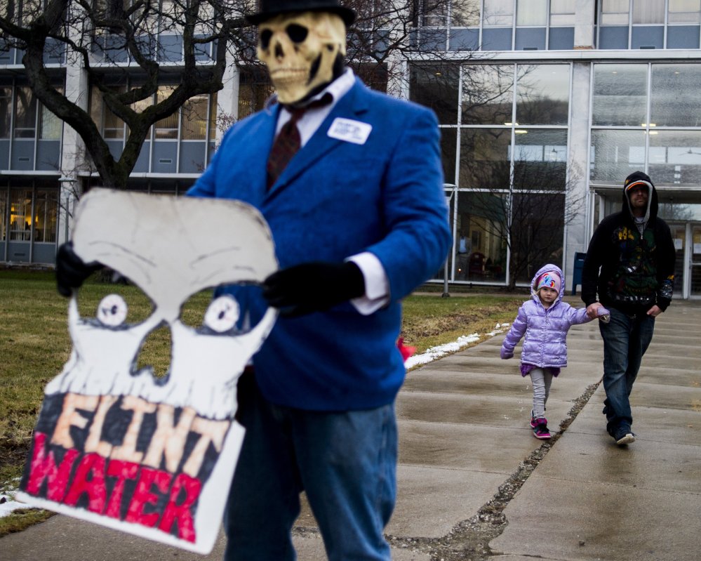 Flint resident Mike Hickey holds the hand of his daughter Natielee, 4, as they walk past activists protesting against Michigan Gov. Rick Snyder's handling of the water crisis on Jan. 8 in Flint. Mich.
The Associated Press