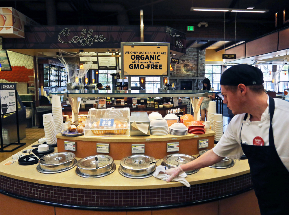 A grocery store employee in Colorado wipes down a soup bar with a sign overhead that says the soups were prepared with organic, GMO-free oils. Maine has a law that requires labeling of genetically engineered food once five contiguous states, including Maine, adopt similar laws by Jan. 1, 2018.