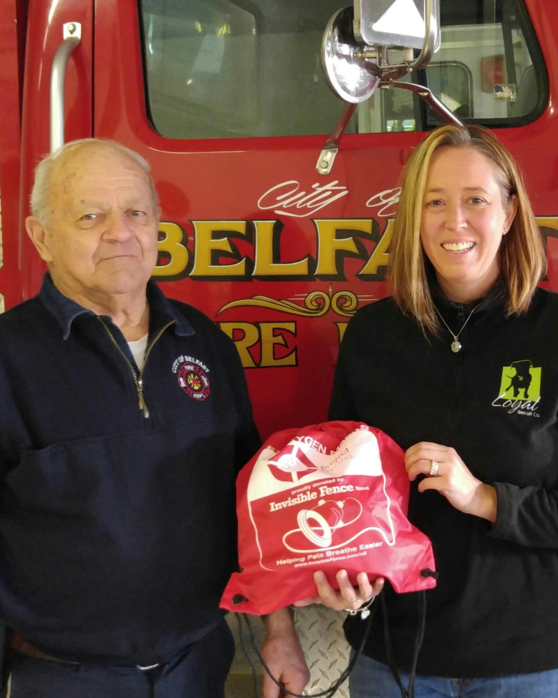 Heidi V. Neal, owner of The Loyal Biscuit Co., presents Belfast Fire Department Chief James Richards with a pet oxygen mask. Funds were raised through the Loyal Biscuit’s partnership with the Maine POM Project.