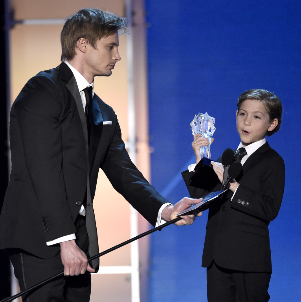 Bradley James, left, holds the microphone for Jacob Tremblay as he accepts the Critics’ Choice Award for best young actor/actress for “Room.”