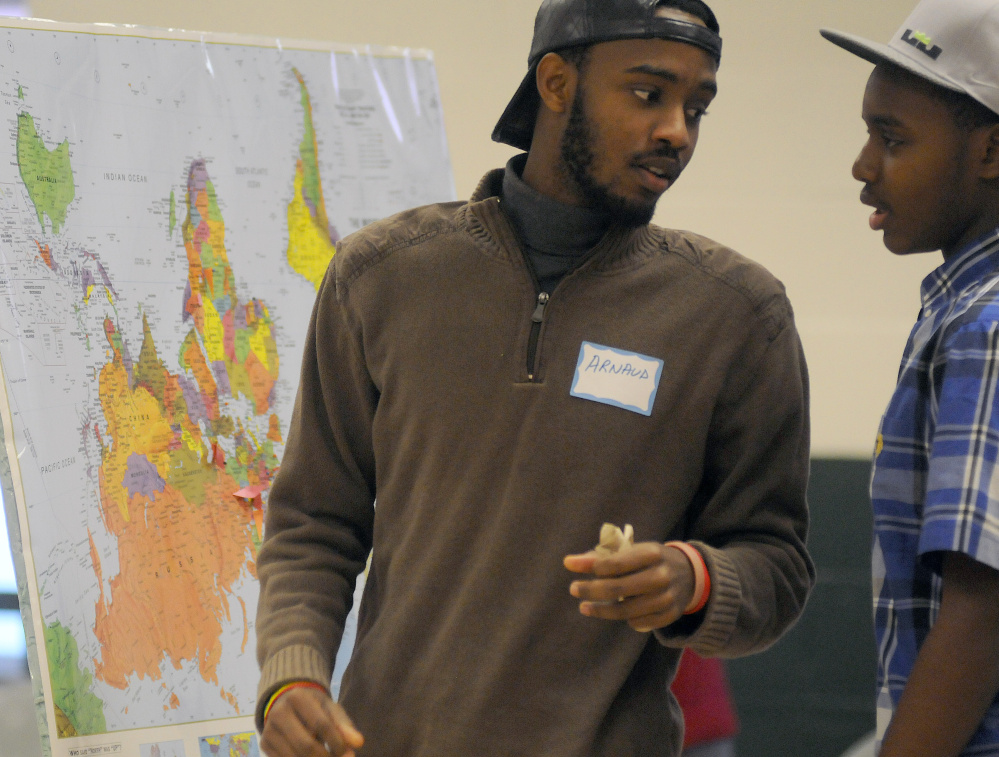 Arnaud Nahimana, left, and his brother, Nelson, place pins on a map of their native country, Burundi, during a Martin Luther King Day forum in Winthrop. The teens live in Biddeford.