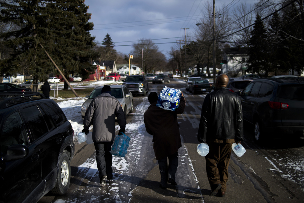 Flint residents Marcus Shelton, Roland Young and Darius Martin walk on an ice-covered street as they retrieve free water in Flint, Mich., in January 2016. Flint’s water became contaminated after Flint switched from the Detroit water system to the Flint River as a cost-cutting move.