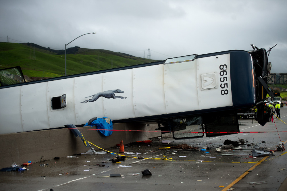 A Greyhound bus that lost traction and became airborne sits atop a concrete highway divider on Tuesday in San Jose, Calif.