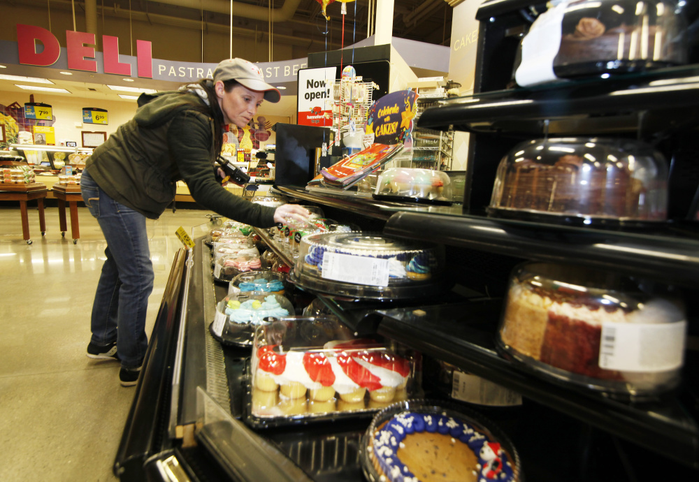 Shannon LeBlanc, bakery service leader at Hannaford in Westbrook, checks the dates on cakes and other bakery items for food pantry donations. Jill Brady/Staff Photographer
