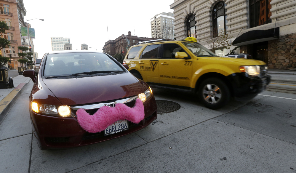 In this Jan. 4, 2013 photo, Lyft driver Nancy Tcheou waits in her car after dropping off a passenger as a taxi cab passes her in San Francisco. The final destination is a mystery, but General Motors is taking another step on its fast-moving journey into new ways of getting around. The company on Thursday, Jan. 21, 2016, announced that it’s formed a brand called “Maven” that will run its car-sharing ventures, including a new one that will begin competing with ZipCar next month in Ann Arbor, Michigan, and spread to other metro areas later this year. GM executives said they expect their main business model of selling cars to people will continue to be large, but they also see big changes coming with ride- and car-sharing. (AP Photo/Jeff Chiu, File)