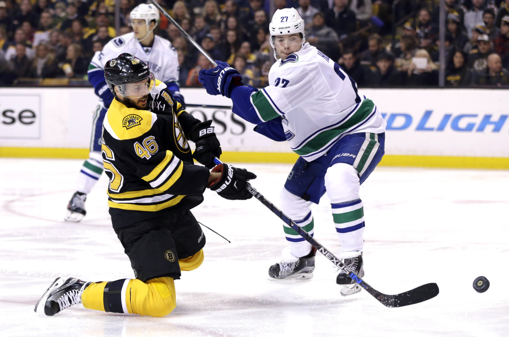 Bruins center David Krejci goes down on a knee in an attempt to control the puck against Vancouver defenseman Ben Hutton in the second period Thursday night in Boston.