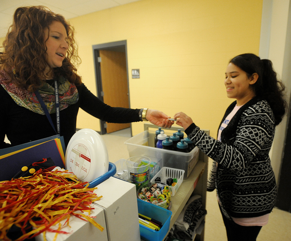 Parker Middle School guidance counselor Meghan O’Brien, left, gives student Joceila Andrade a thumb drive in a store at the school where students “spend” the red tickets that they earn for good classroom behavior.
