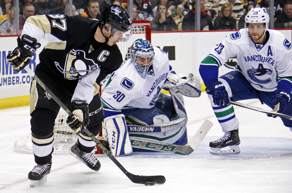 Vancouver goalie Ryan Miller and defenseman Alexander Edler try to cut off Sidney Crosby’s options during Saturday’s game against the Penguins. Pittsburgh won, 5-4.