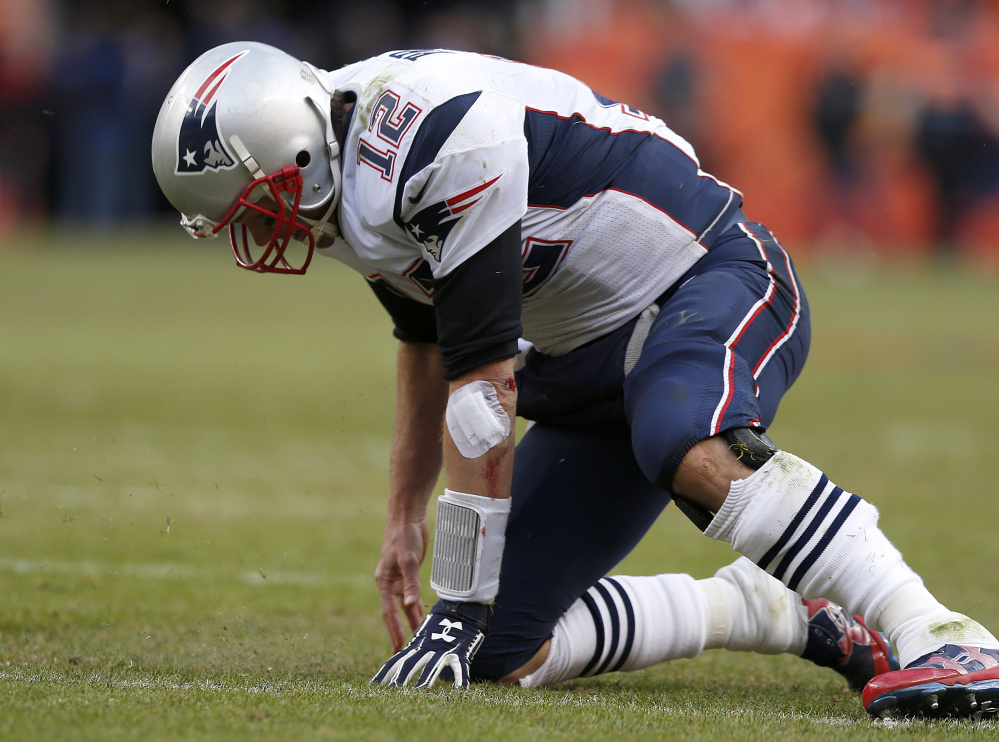 New England Patriots quarterback Tom Brady gets up after taking a hit during the second half of the AFC championship game Sunday against the Denver Broncos.