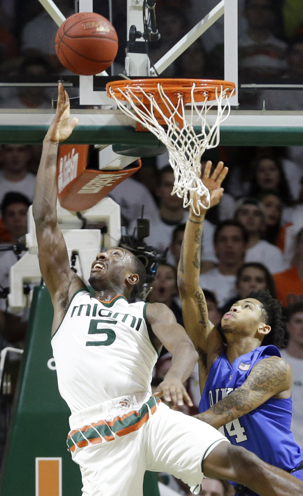 Miami’s Davon Reed, left, scoops a shot past Duke’s Brandon Ingram during the Hurricanes’ win Monday in Coral Gables, Florida.