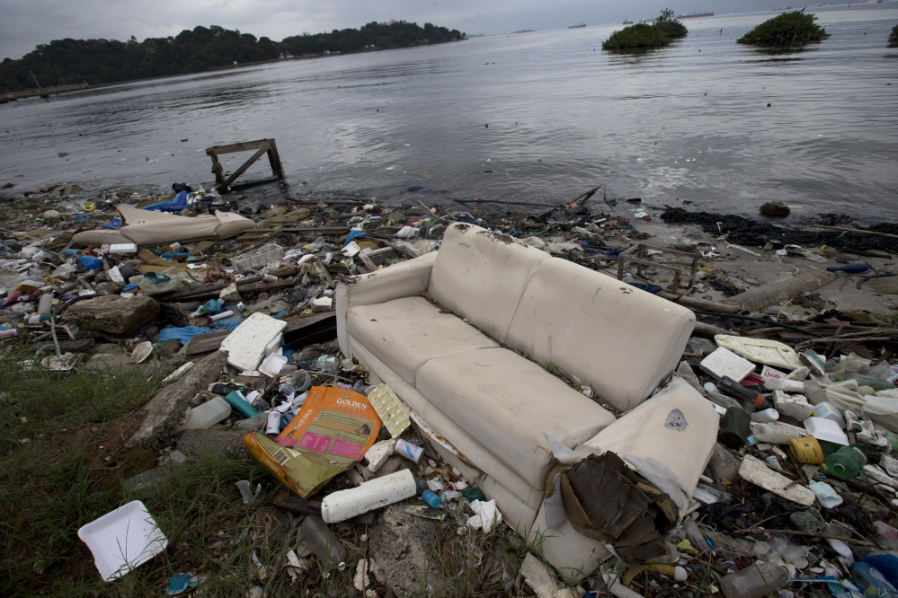 FILE - In this June 1, 2015 file photo, a discarded sofa litters the shore of Guanabara Bay in Rio de Janeiro, Brazil. About 1,600 athletes will compete in Rio during the 2016 Summer Olympics. Hundreds more will be involved during the subsequent Paralympics. Experts say athletes will be competing in the viral equivalent of raw sewage with exposure to dangerous health risks almost certain. Many sailors have described the conditions as "sailing in a toilet" or an "open sewer." (AP Photo/Silvia Izquierdo, File)