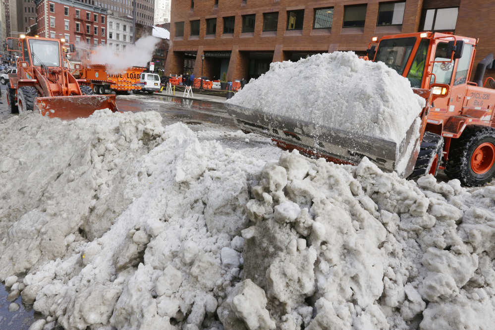 A pair of New York City Department of Sanitation front-end loaders prepare plowed snow for a melter, background left, in lower Manhattan in New York on Tuesday.