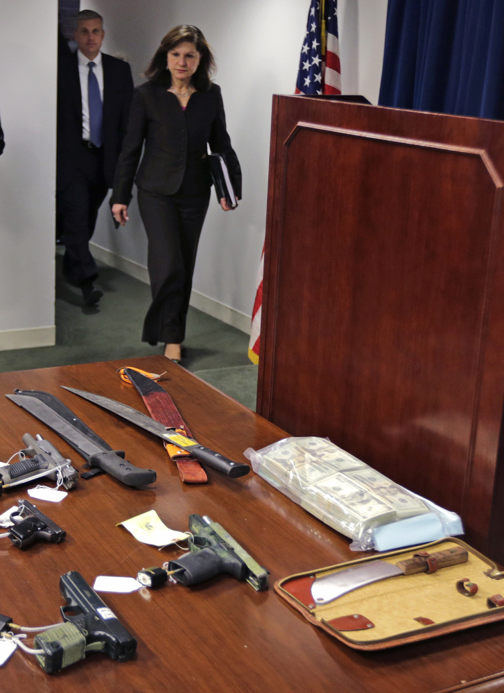 U.S. Attorney Carmen Ortiz walks towards a podium, with weapons and cash on display on a table, during a news conference in Boston, Friday, Jan. 29, 2016. Authorities say they have charged over 50 members of the MS-13 gang in and around Boston. The gang is notoriously violent and known for using machetes to kill victims. According to court documents, in 2012, MS-13 became the first and remains the only street gang to be designated by the U.S. government as a "transnational criminal organization." Behind Ortiz is F.B.I. Special Agent in Charge Harold Shaw. (AP Photo/Charles Krupa)