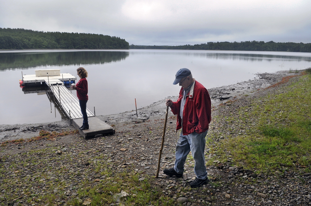 Stan Whittier walks on the shore of Clary Lake in Jefferson in 2015 while his daughter, Jane Roy, stands on the family’s dock. It’s been nearly three years since property owners around Clary Lake in Jefferson and Whitefield appealed to the state to intervene about a low water level.