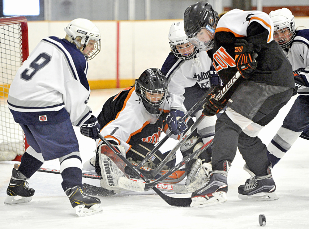 The puck squirts away from Winslow/Erskine goalie Kiana Richards as teammate Bailey Robbins fights for the rebound with Madi McCallum, left, Keeley Arnold, center, and Colleen Sullivan of Yarmouth/Freeport/Gray-New Gloucester during a girls’ hockey game Saturday.