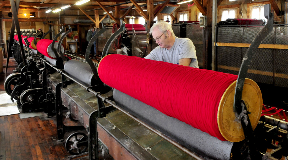 Bartlettyarns employee Steve White loads large rolls of wool onto a spinning mule, a machine that spins wool into a stronger skein of yarn. Below, mill owner Lindsey Rice shows off a machine called a duster.
