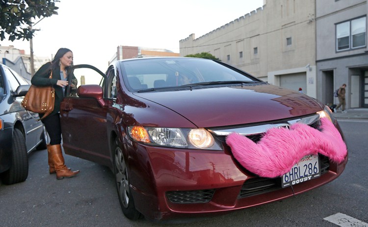 A Lyft passenger gets into a car with the company's glowing mustache logo in San Francisco. Lyft has managed to avoid much of the controversy that’s been dogging Uber, and the image it projects appears to be a kinder, gentler one. The Associated Press
