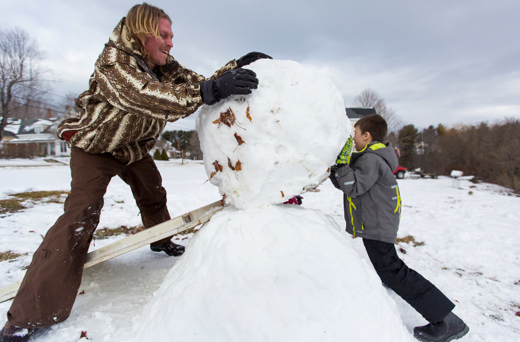 Ryan Bellemare, left, and his son Blake, 5, use a ramp to roll the middle section of a snowman into place Sunday in Auburn. The snowball, which weighed an estimated 250 pounds, broke another wooden ramp just minutes earlier. A winter storm on Friday blanketed southern Maine with wet snow -- ideal for making snowballs and snowmen.