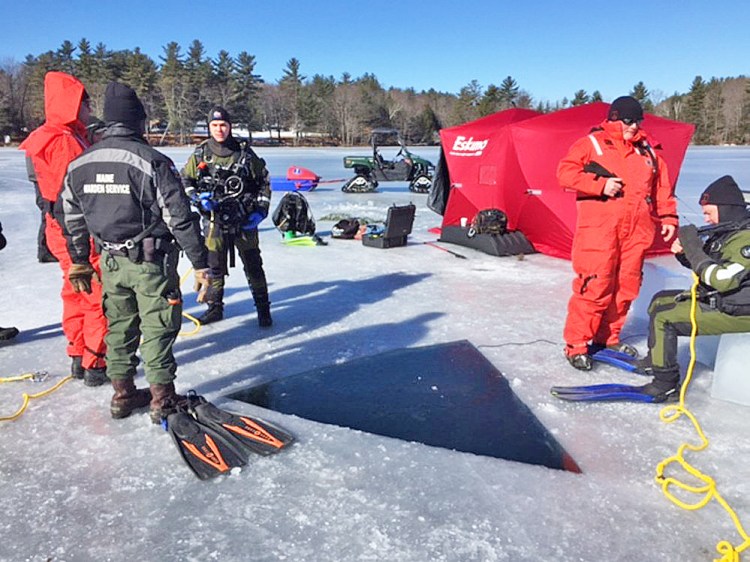 Maine Game Warden divers prepare to enter the water Monday on Salmon Lake in North Belgrade in search of an all-terrain vehicle. 