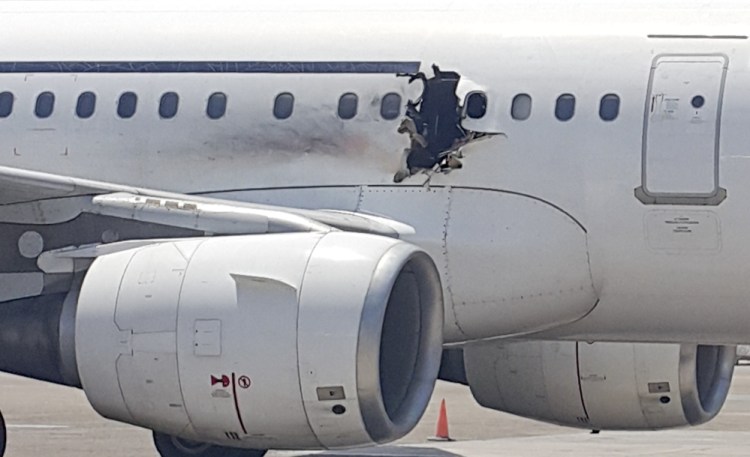 A hole is photographed in a plane operated by Daallo Airlines as it sits on the runway of the airport in Mogadishu, Somalia.