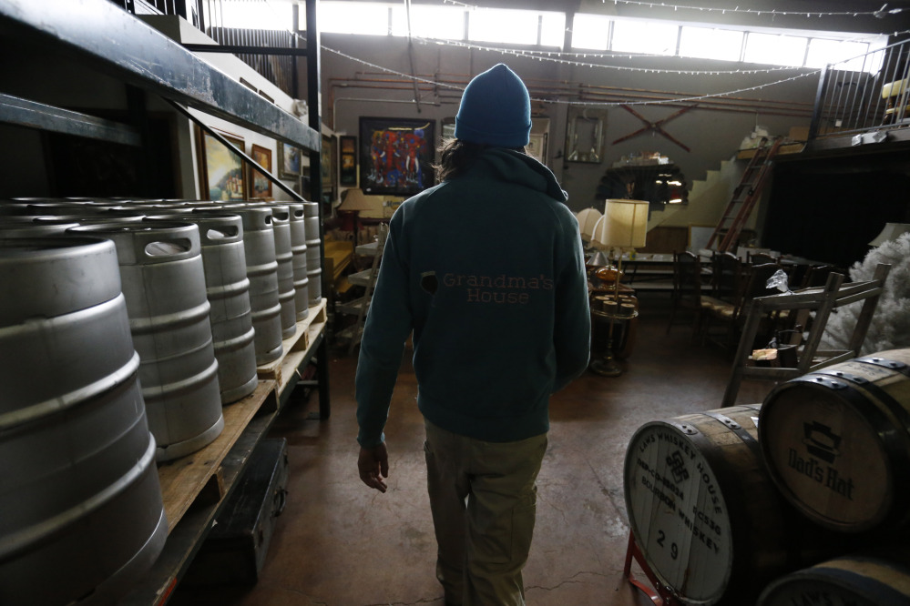 Matthew Fuerst, the founder and owner of Grandma’s House nano-brewery and tasting room, walks past barrels of beer in the back room of his tasting room in Denver. (AP Photo/Brennan Linsley)