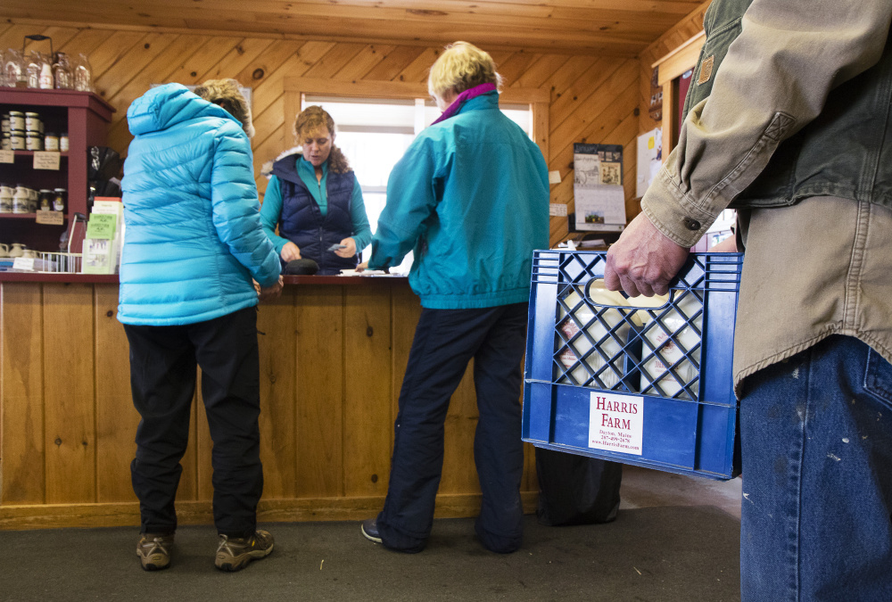 A customer waits to purchase milk as Rachel Harris waits on cross-country ski customers.