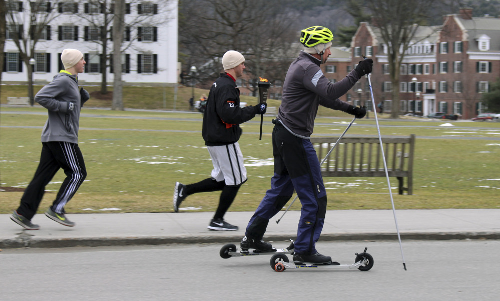 David McCrillis, right, on roller-skis and Garrett Hubert, center, carrying the torch, set off Friday, Feb. 5, 2016, from the Dartmouth Outing Club in Hanover, N.H., for the 30-mile trek to the Newport town common to launch the 100th Newport Winter Carnival. They are following the path that McCrillis’s grandfather, carnival founder and Dartmouth College student John McCrillis, strapped on cross-country skis to make the journey to the first carnival in 1916. Organizers believe it is the oldest continuously run town winter carnival in the country. (AP Photo/Lynne Tuohy)