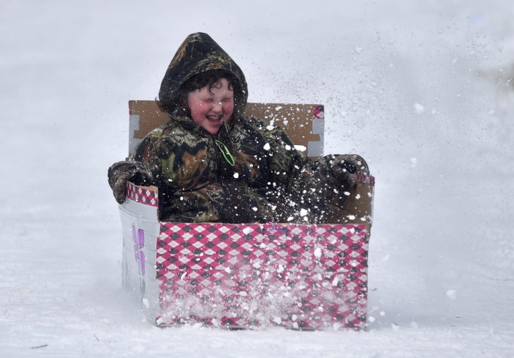A competitor in the Box Sled Derby Race zips through a spray of snow Saturday at the annual Winter Carnival at Lake George Regional Park in Skowhegan.