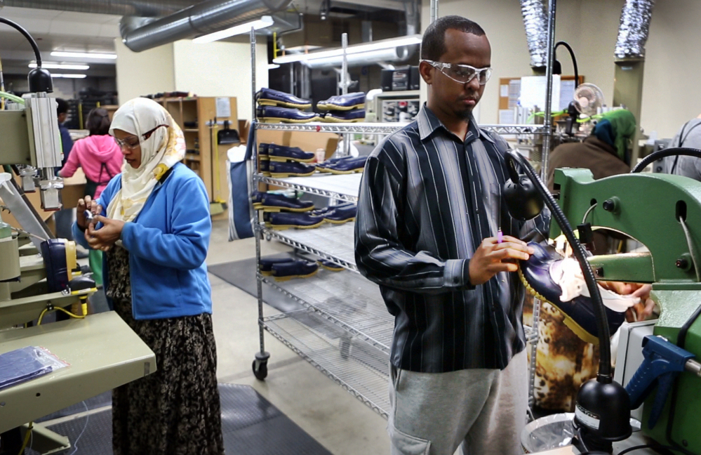 Abdi Said, right, trims the rubber bottoms of Bean Boots at an L.L. Bean factory in Lewiston. Said, a refugee, was originally put in San Jose, California, before he moved cross-country to Lewiston. “We are working hard and we’re going to school and everything - like regular American people. They see that we are not different,” he said.