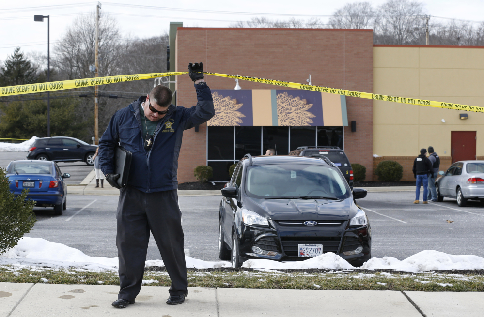 An investigator walks beneath police tape at the scene of a shooting at a shopping center in Abingdon, Md., on Wednesday.