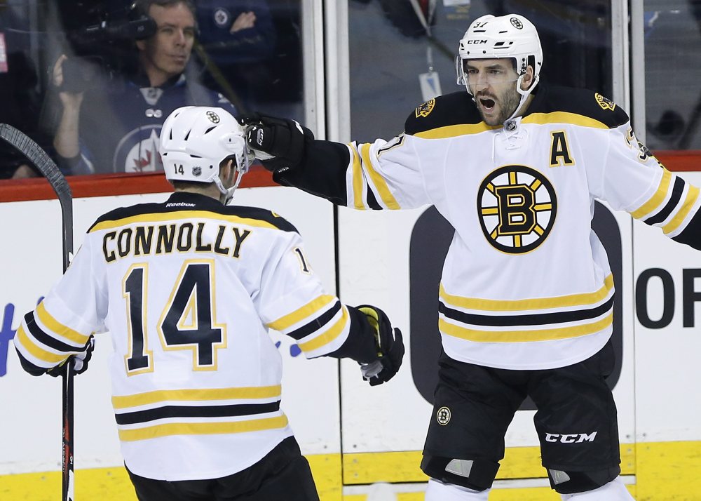 The Bruins’ Brett Connolly (14) and Patrice Bergeron celebrate Bergeron’s goal early in the first period Thursday night in Winnipeg, Manitoba. Bergeron scored two goals in the Bruins’ win.