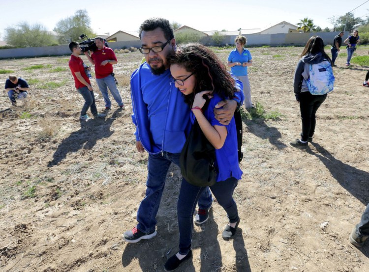 A father and daughter reunite in a vacant field, Friday, in Glendale, Ariz., after two students were shot and killed at Independence High School in the Phoenix suburb.