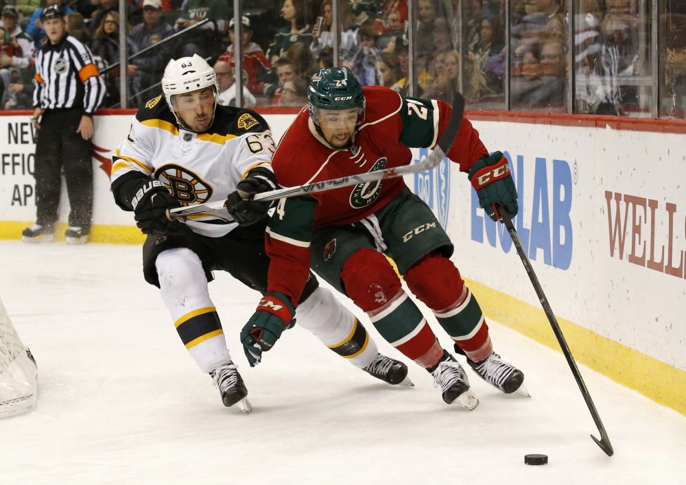 Boston left wing Brad Marchand, left, and Minnesota Wild defenseman Matt Dumba chase the puck during the second period of an NHL hockey game in St. Paul, Minn., Saturday. The Bruins won the game, 4-2.