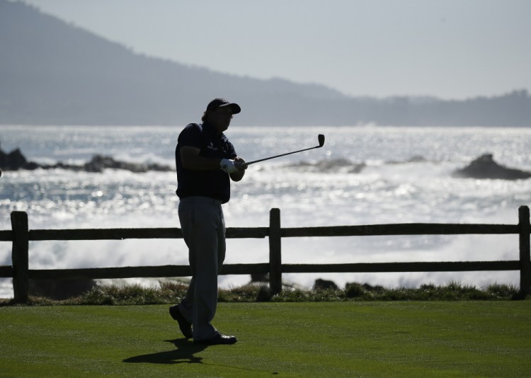 Leader Phil Mickelson is silhouetted as he hits from the 18th tee during the third round of the AT&T Pebble Beach National Pro-Am golf tournament Saturday at Pebble Beach, California.
