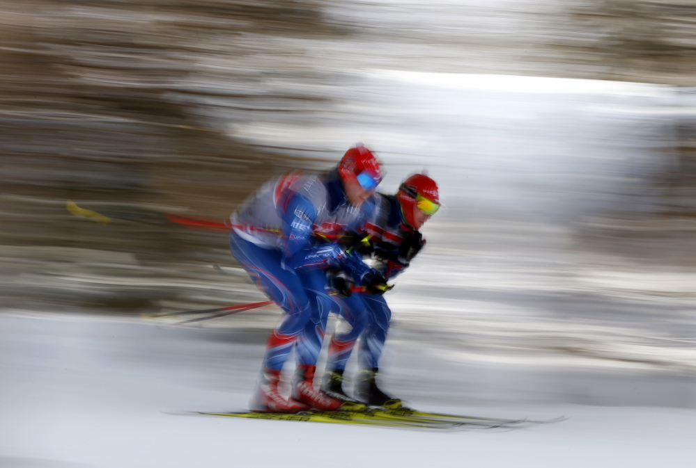 In this image taken with a slow shutter speed, members of the Czech Republic team glide together while testing wax and snow conditions prior to the relay competition at the World Cup Biathlon, Saturday, Feb. 13, 2016, in Presque Isle, Maine. (AP Photo/Robert F. Bukaty)
